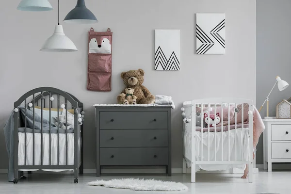 침대 2 개와 서랍 장이 있는 트 렌 디 한 아기 침실의 벽에 분홍색 조직자 — 스톡 사진