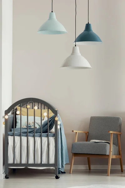 Grey wooden crib in fashionable scandinavian baby bedroom interior
