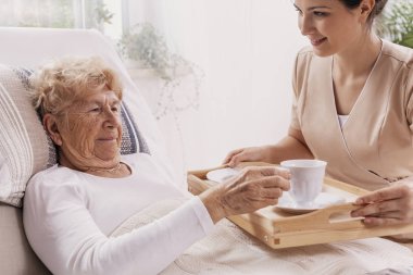 Bej kahve üst düzey kadın hastaya hizmet veren tek tip yardımcı gönüllü