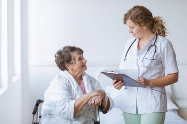 Ped ve stetoskop ve baston ile yaşlı büyükanne ile genç stajyer doktor