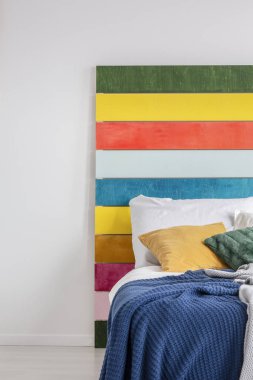 Beyaz duvara karşı duran bir gökkuşağı resmi yakın çekim, beyaz yatak odası iç rahat bir yatak arkasında. Gerçek fotoğraf