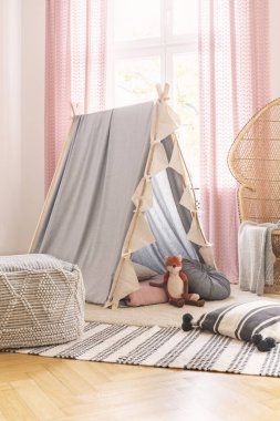 Pembe perdeler ve yastıklar ile kız odasında tilki oyuncak ile çadır yakınında desenli halı üzerinde Puf. Gerçek fotoğraf