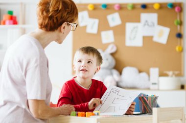 Cute little boy with problems during meeting with therapist clipart