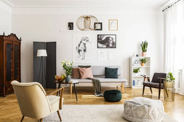 Poltrona retrò beige e pouf sul tappeto accogliente in salotto contemporaneo interno con divano grigio e mobili vintage — Foto Stock