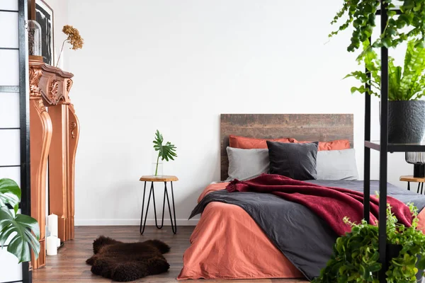 Eigentijdse slaapkamer met koraal lakens, koperachtige open haard en — Stockfoto