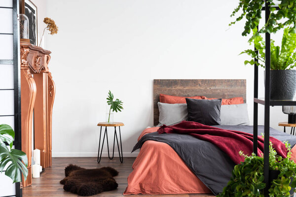 Contemporary bedroom with coral bedsheets, coppery fireplace and