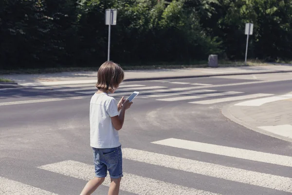 Schoolboy with mobile phone on pedestrian crossing going home — Stock Photo, Image