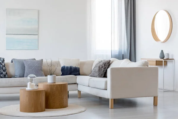 Pintura abstracta azul y blanca y espejo en marco de madera en elegante salón interior con sofá de esquina y mesa de centro — Foto de Stock