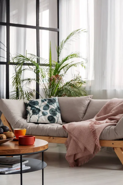 Comfortable beige scandinavian settee with patterned pillow in bright living room interior — Stock Photo, Image