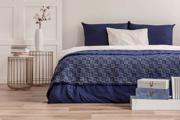 Bloemen in vaas op nachtkastje naast King size bed met marineblauw beddengoed — Stockfoto