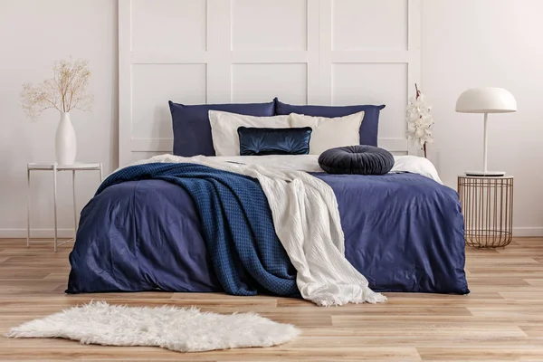 Cuscino rotondo in velluto su letto king size con lenzuola blu e bianche — Foto Stock