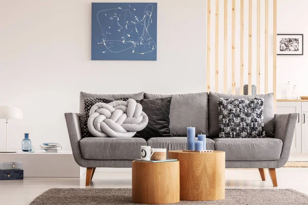 Blauwe abstracte schilderij op witte muur van de hedendaagse woonkamer interieur met grijze bank met kussens — Stockfoto