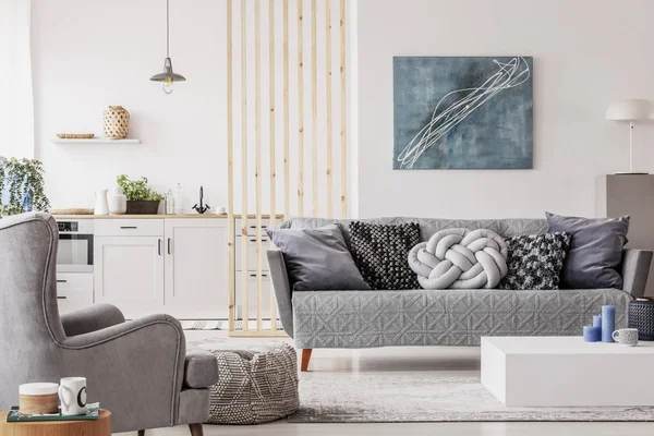 Offene Studiowohnung mit kleiner weißer Küche und Wohnzimmer mit grauer Couch und Holztisch — Stockfoto