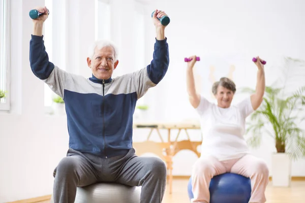 Senior man exercising with weights in his retirement home — Stock Photo, Image