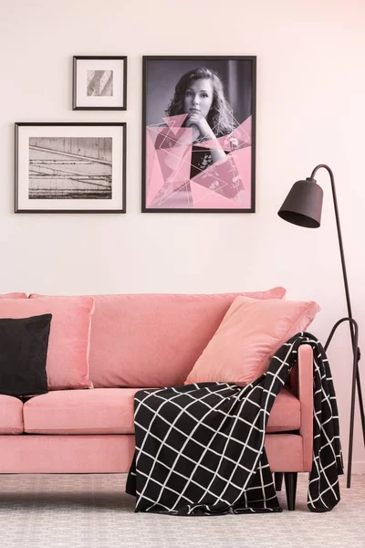 Галерея плакатов на белой стене в модном интерьере гостиной с розовым диваном и промышленной лампой — стоковое фото