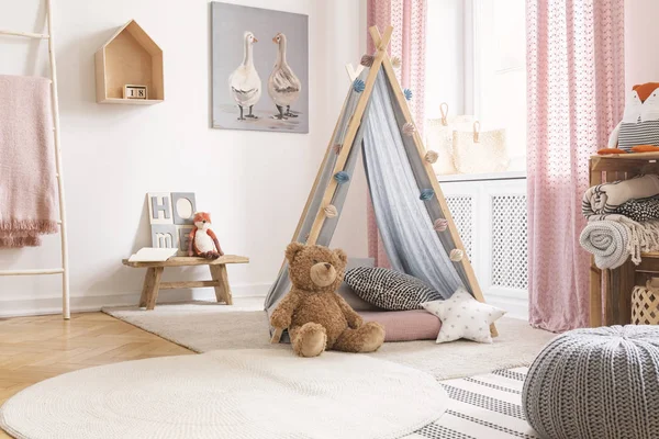 Teddybär und Sternkissen vor dem Zelt im Kinderzimmerinnenraum mit Hocker und Poster. echtes Foto — Stockfoto