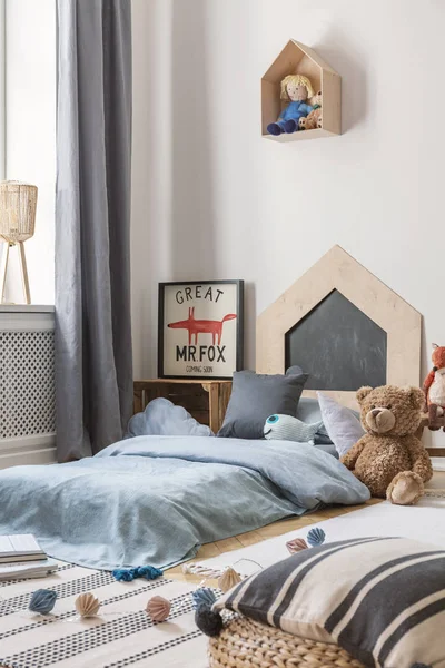 Peluche de juguete al lado de la cama azul con almohadas en el interior del dormitorio de los niños con cartel de zorro y muñeca. Foto real — Foto de Stock