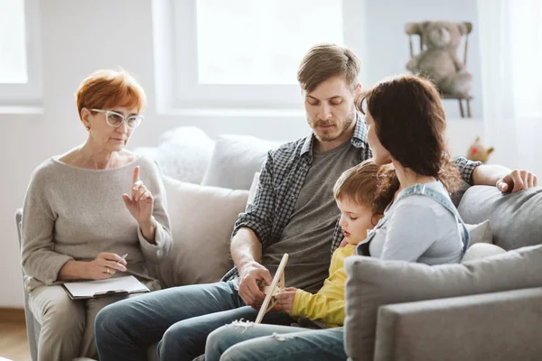 Parents and therapist are sitting on the couch during a meeting about their child