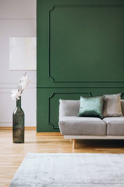 Şık oturma odası iç gri settee yanında vazo gibi büyük yeşil şişe şeklinde Beyaz çiçekler