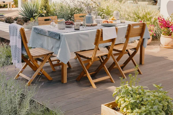 Πραγματική φωτογραφία με τραπέζι φαγητού με ξύλινες καρέκλες στη βεράντα — Φωτογραφία Αρχείου