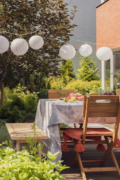 Real photo of lamps hanging in a garden above a table and chairs — Stock Photo, Image