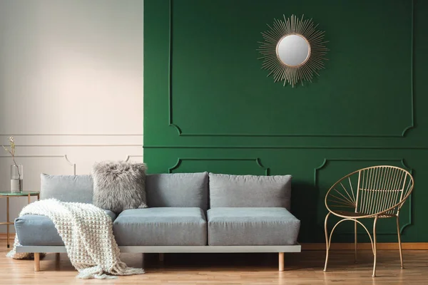 Zlaté slunce jako zrcadlo na zelené stěně interiéru obývacího pokoje se skandinávským pohovkou s polštáři — Stock fotografie