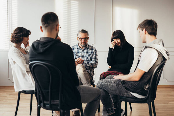 Young woman crying during widow and widowers support group meeting
