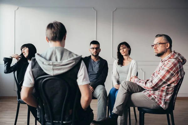 Hombres y mujeres que escuchan sobre los problemas de ansiedad de los adolescentes en la escuela durante la terapia de grupo — Foto de Stock