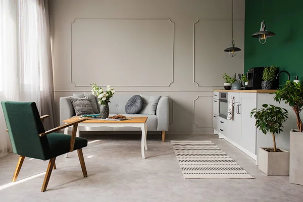 Открытая кухня и интерьер гостиной с удобным диваном и ретро-креслом — стоковое фото