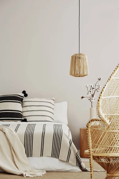Черно-белое постельное белье на удобной двуспальной кровати в элегантном интерьере спальни с павлиньим стулом и копировальным местом на пустой стене — стоковое фото
