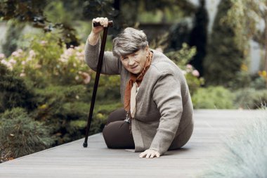 Nefes darlığı saldırısından sonra yardım bekleyen bastonlu zayıf yaşlı kadın