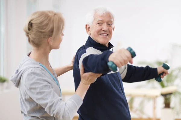 Senior man after stroke at nursing home exercising with professional physiotherapist — Stock Photo, Image