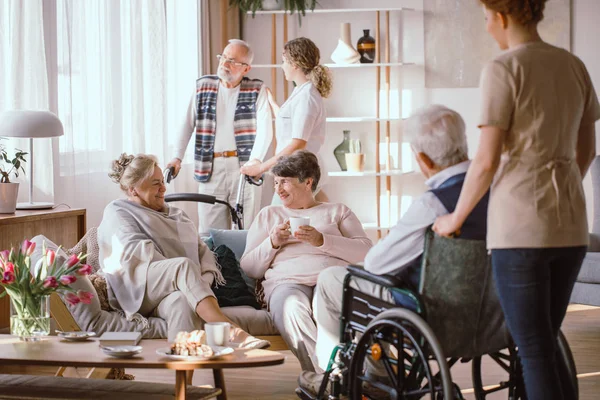 Пожилые мужчины и женщины разговаривают в общей комнате в доме престарелых — стоковое фото