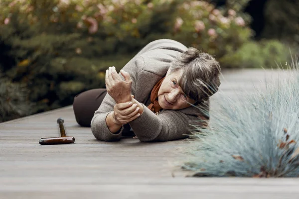 Weak elderly woman lying on the floor and waiting for help after heart attack — Stock Photo, Image