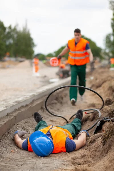 Accidente durante la construcción de la carretera, trabajador lesionado acostado en el suelo —  Fotos de Stock