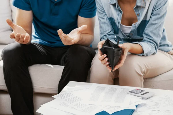 Young married couple sitting in living room with empty wall and pile of bills — Stock Photo, Image