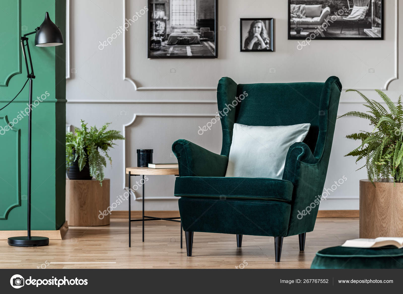 pillow on emerald green armchair in elegant living room with black and  white photos on grey wall 267767552