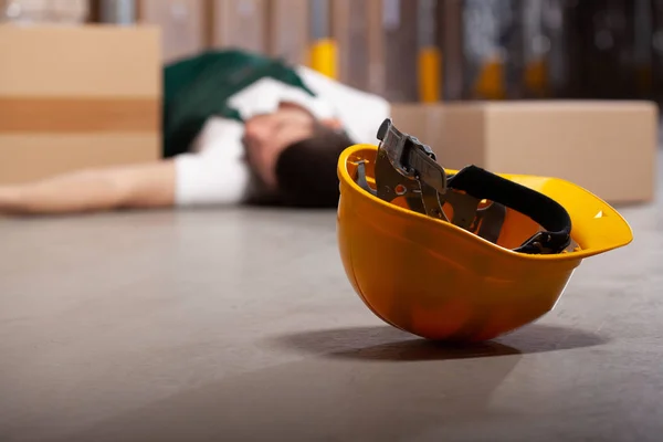Żółty kask na podłodze po niebezpiecznym wypadku w magazynie podczas pracy — Zdjęcie stockowe