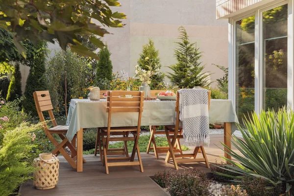 Lantern next to wooden chairs and table on the terrace of house with plants and blanket. Real photo — Stock Photo, Image