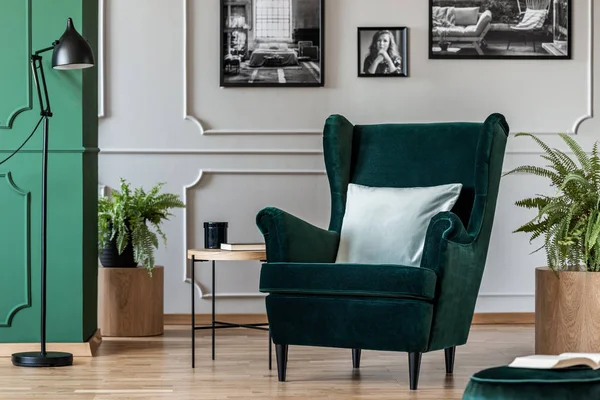 Polštář na smaragdově zeleném křesle v elegantním obývacím pokoji s černými a bílými fotografiemi na šedé stěně — Stock fotografie