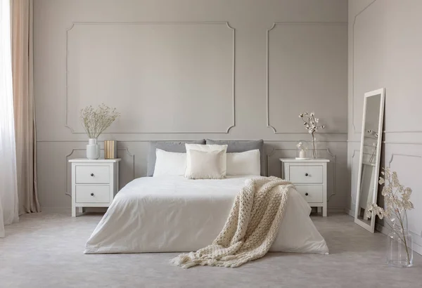 Bloemen op nachtkastje tafel in heerlijke slaapkamer interieur met grijs en wit design — Stockfoto