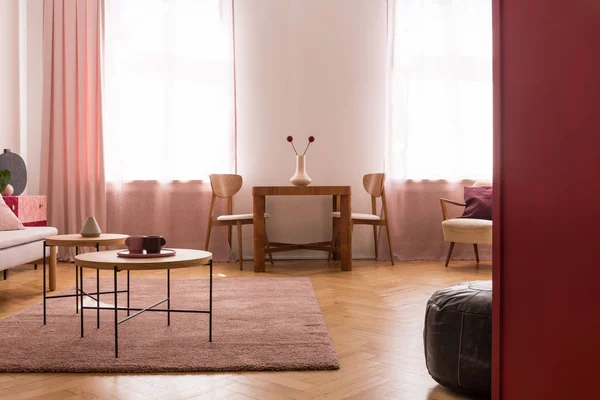 Mesas de madeira em tapete roxo no interior da sala de estar com cortinas rosa na janela. Foto real — Fotografia de Stock