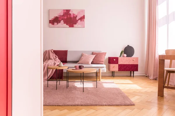 stock image Poster above couch with pink pillows in loft interior with wooden tables on purple carpet. Real photo