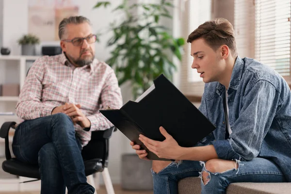 Mladý muž a senior terapeut během setkání profesionálních poradců — Stock fotografie