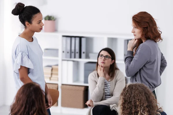 Two brave women standing and looking at each other during role paying at psychotherapy support meeting — Stock Photo, Image