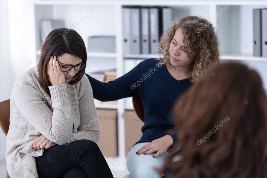 Young woman supporting sad patient at Women's issues support group