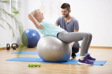 Fizyoterapist ile oturum sırasında jimnastik topu egzersiz orta yaş sarışın kadın