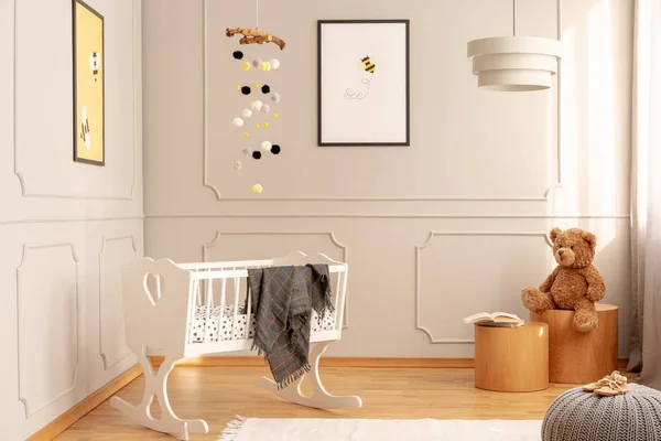 Arı posteri, oyuncak ayı ve lambayla dolu rahat bir bebek odasında beyaz bir beşik. Gerçek fotoğraf. — Stok fotoğraf