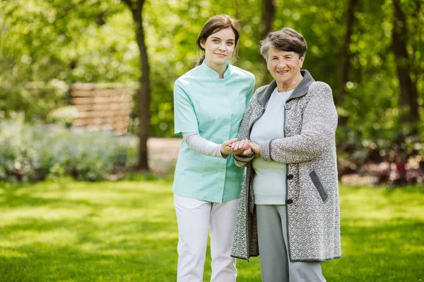 Молода медсестра з літньою жінкою в саду — стокове фото