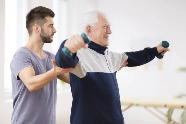 Homem idoso após acidente vascular cerebral em casa de repouso exercitando-se com fisioterapeuta profissional — Fotografia de Stock